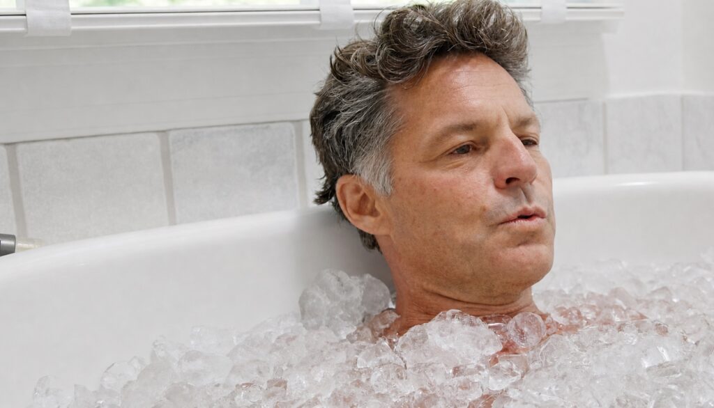John Hoekman submerged to the neck in a bathtub filled with ice, exhaling slowly, eyes open
